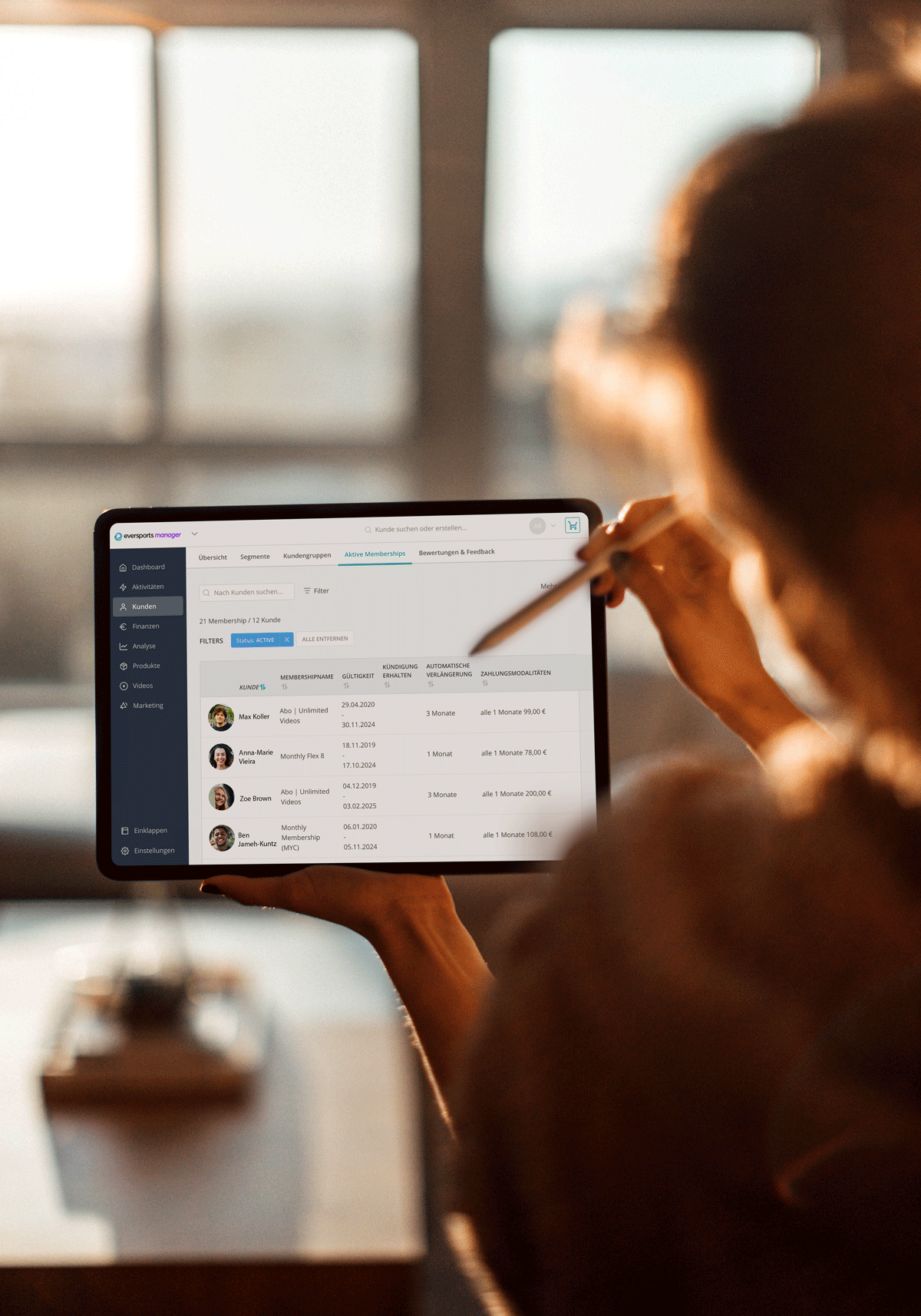 Person holding a tablet displaying a dashboard with user profiles and data in the Eversports Manager