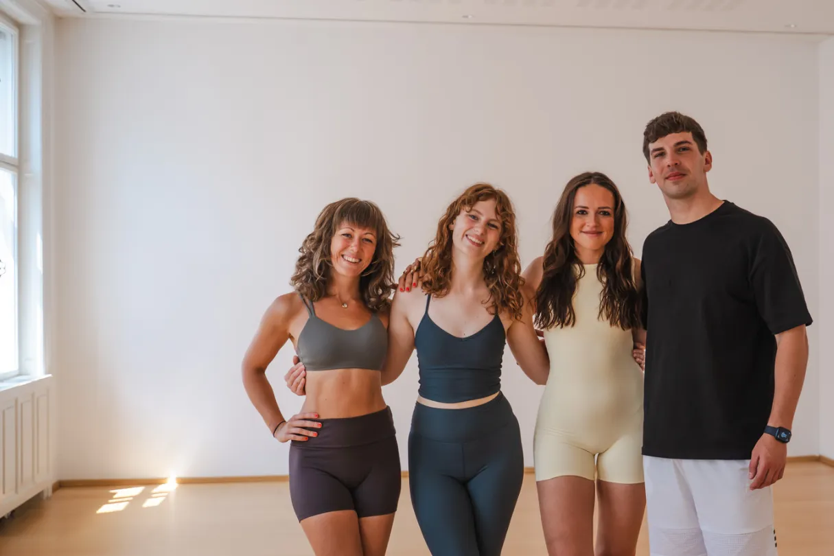 Vier Eversports-Mitarbeiter:innen, die sich an der Taille halten und in einem Yogaraum lächeln.