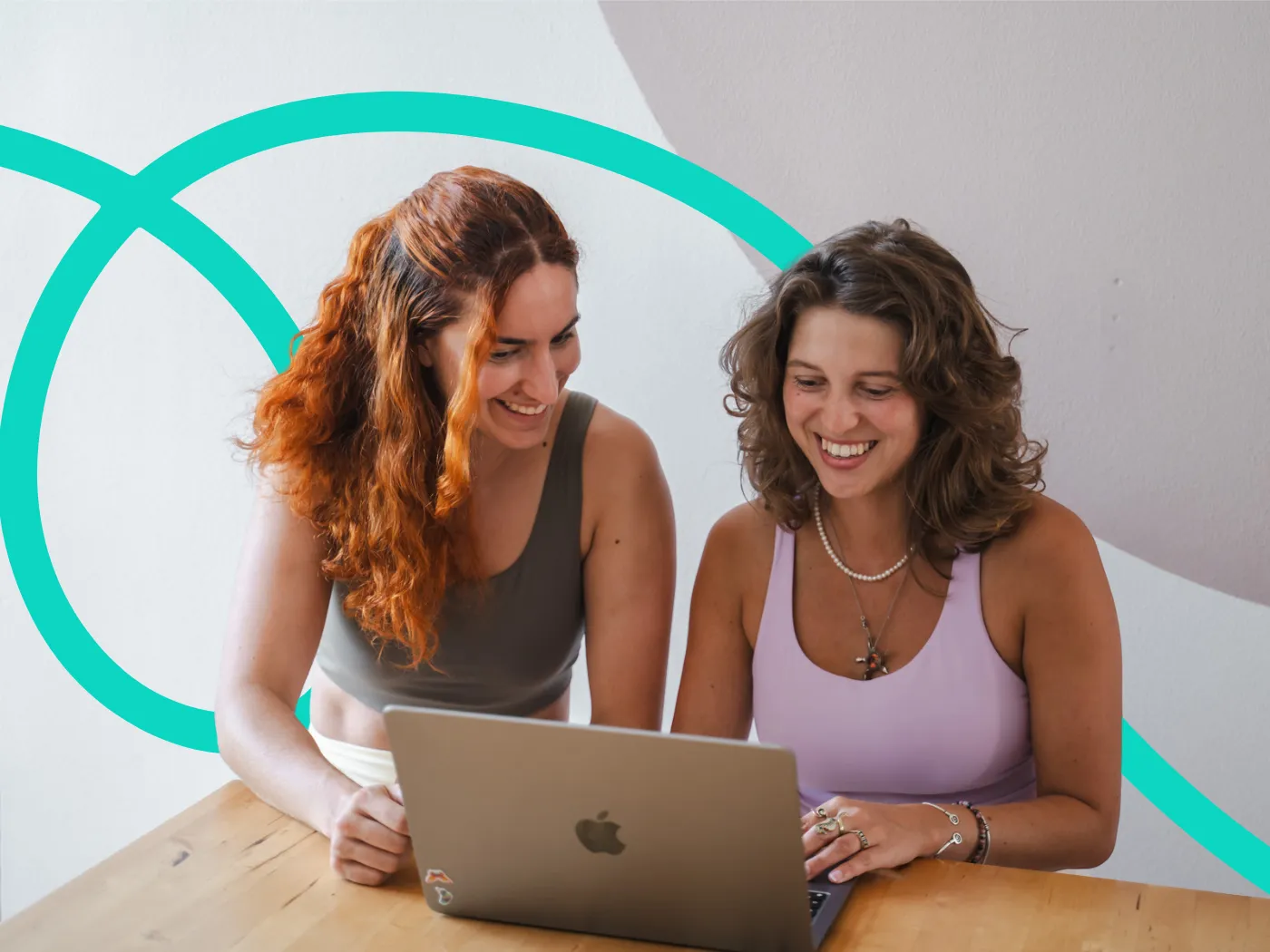 Zwei Frauen lächeln und schauen sich die Eversports Manager Software auf einem Laptop an.