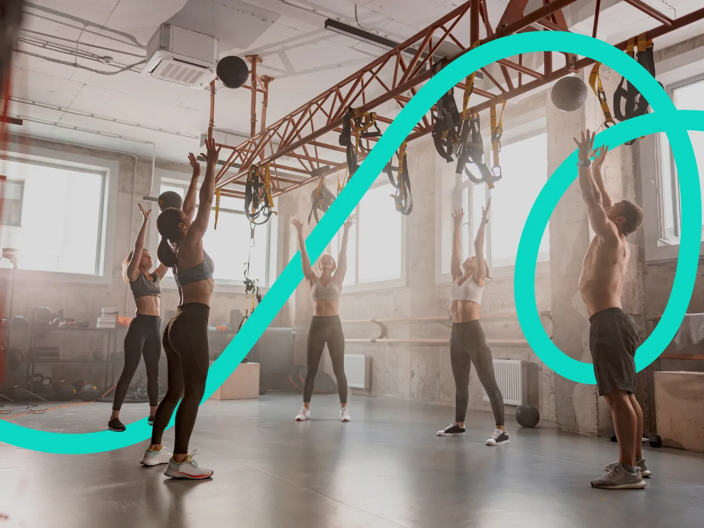 Personen in Sportkleidung trainieren in einem Fitnessstudio, heben Medizinbälle über den Kopf, umgeben von Trainingsgeräten und natürlichem Licht.