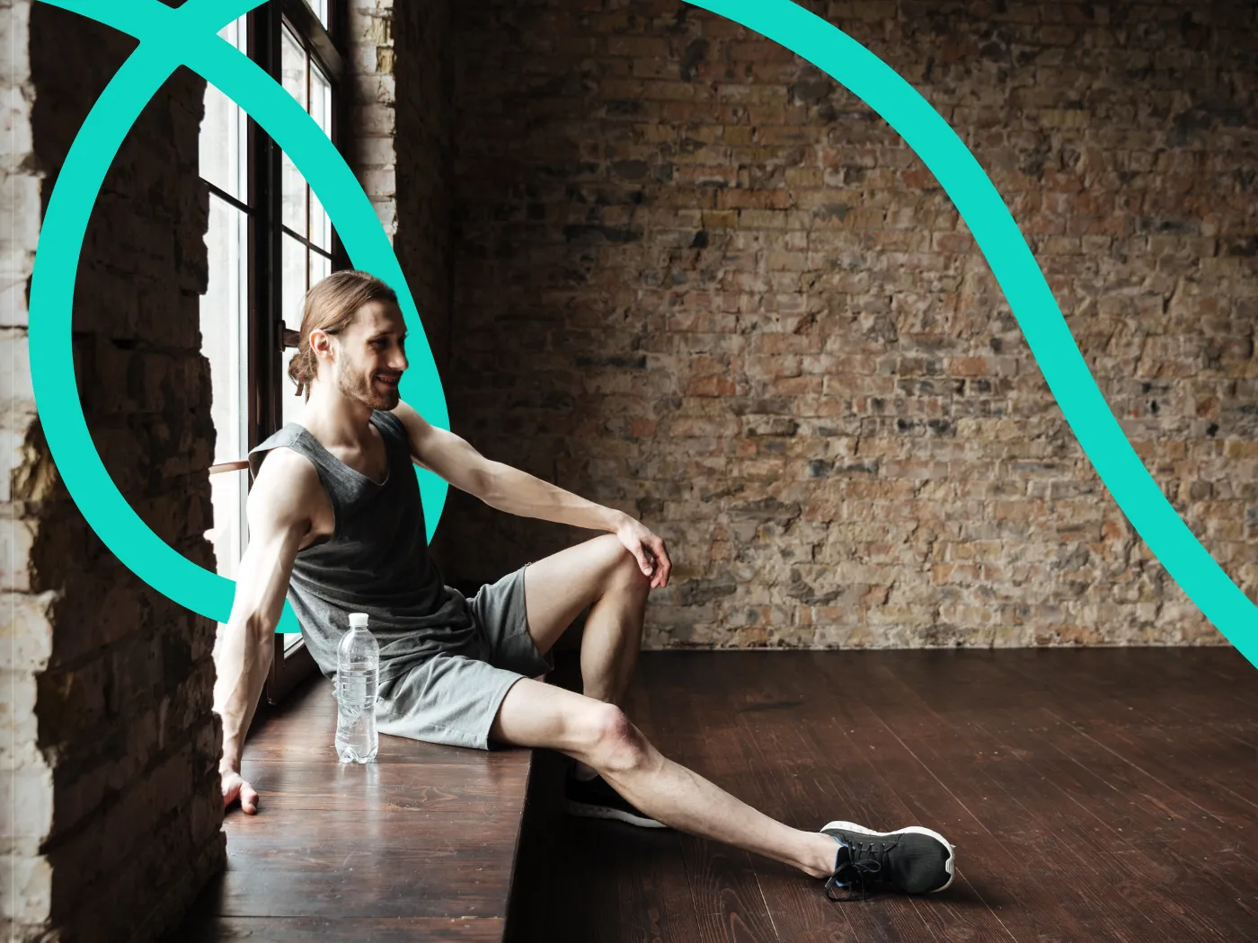Ein Mann in Sportkleidung sitzt auf einer Fensterbank in einem Raum mit Backsteinwänden, lächelt, neben ihm steht eine Wasserflasche.