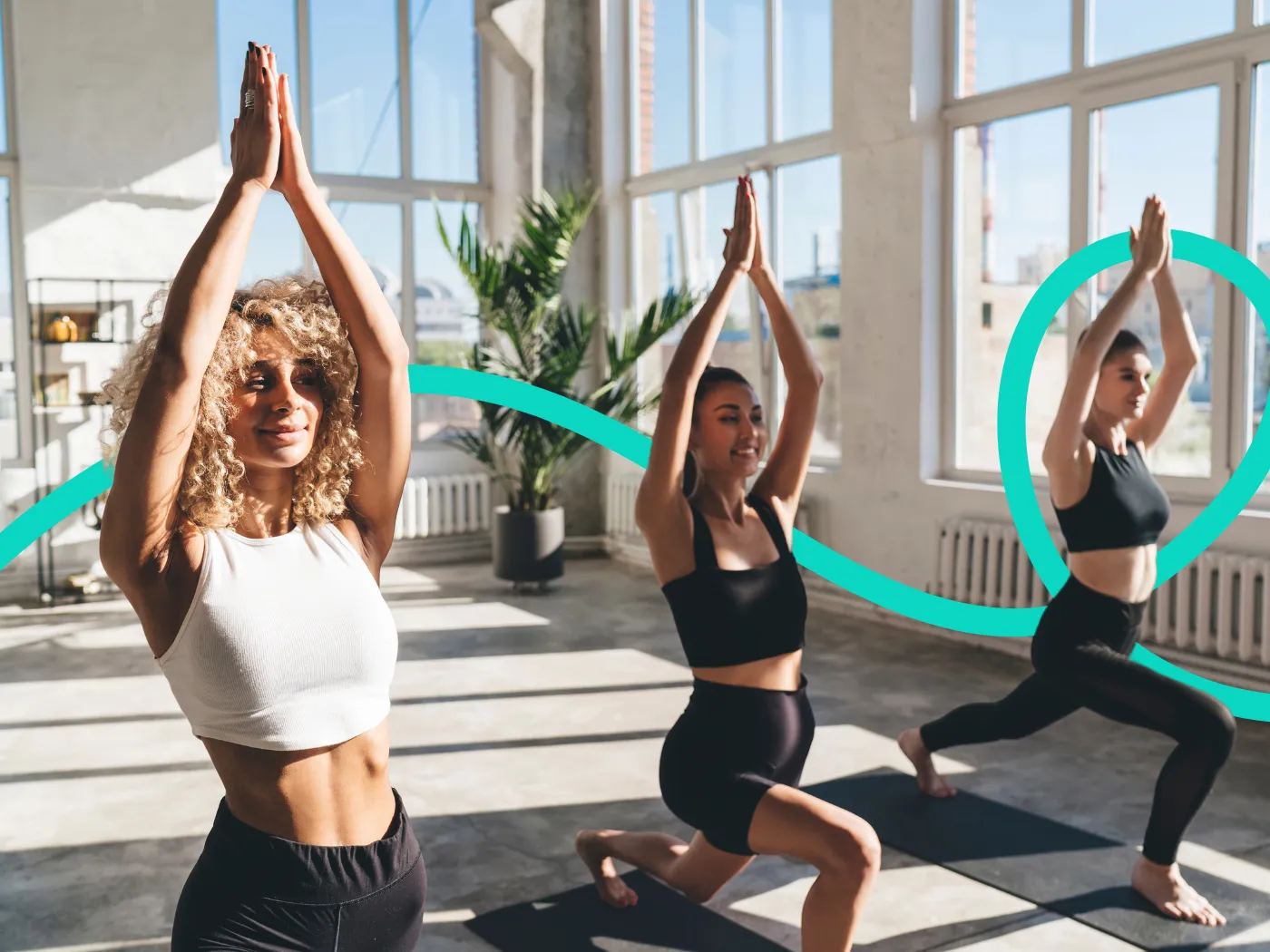 Drei Frauen praktizieren Yoga in einem sonnenbeschienenen Studio.