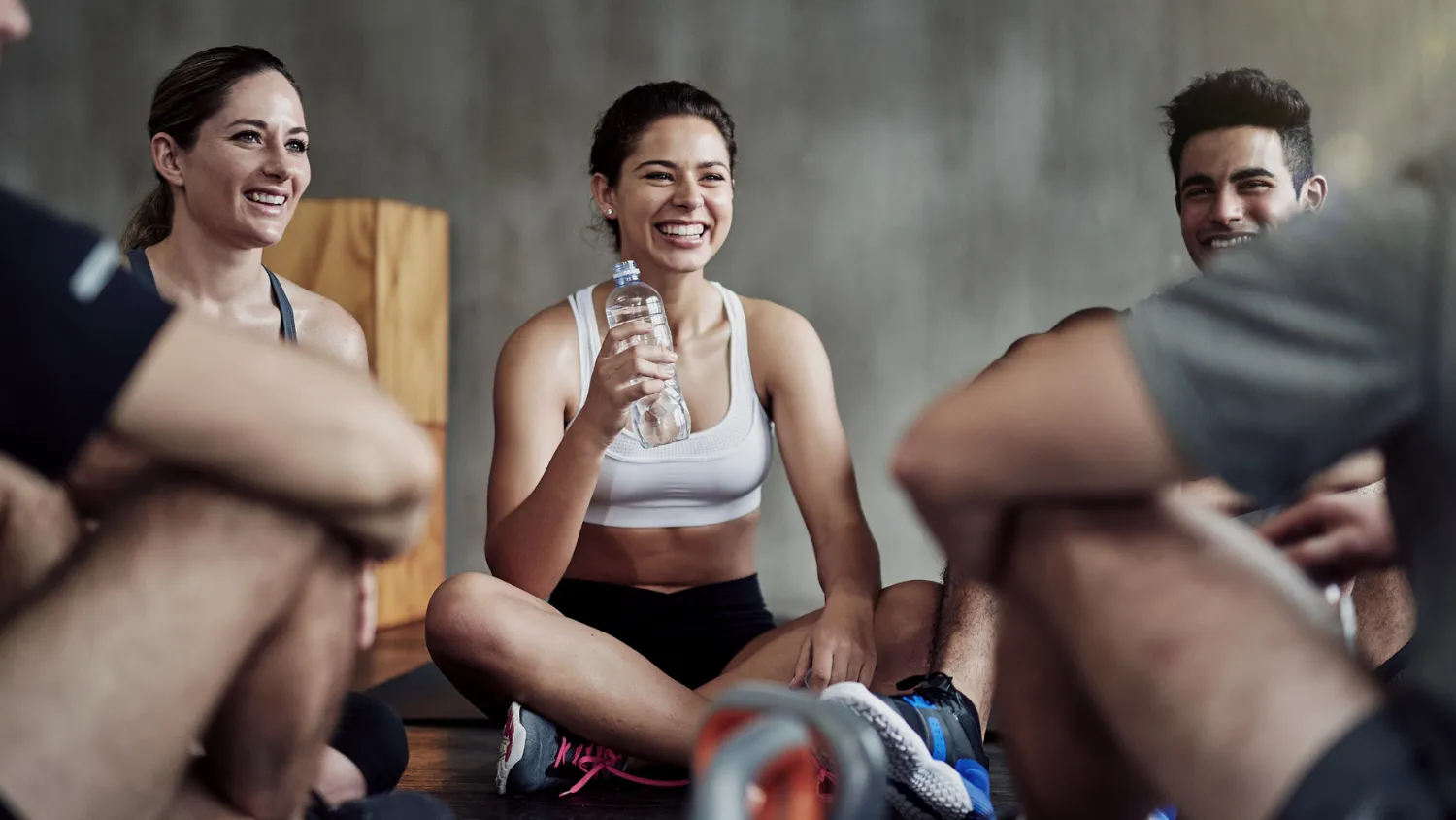 Gruppe von Personen sitzt am Boden in Sportkleidung und lächeln