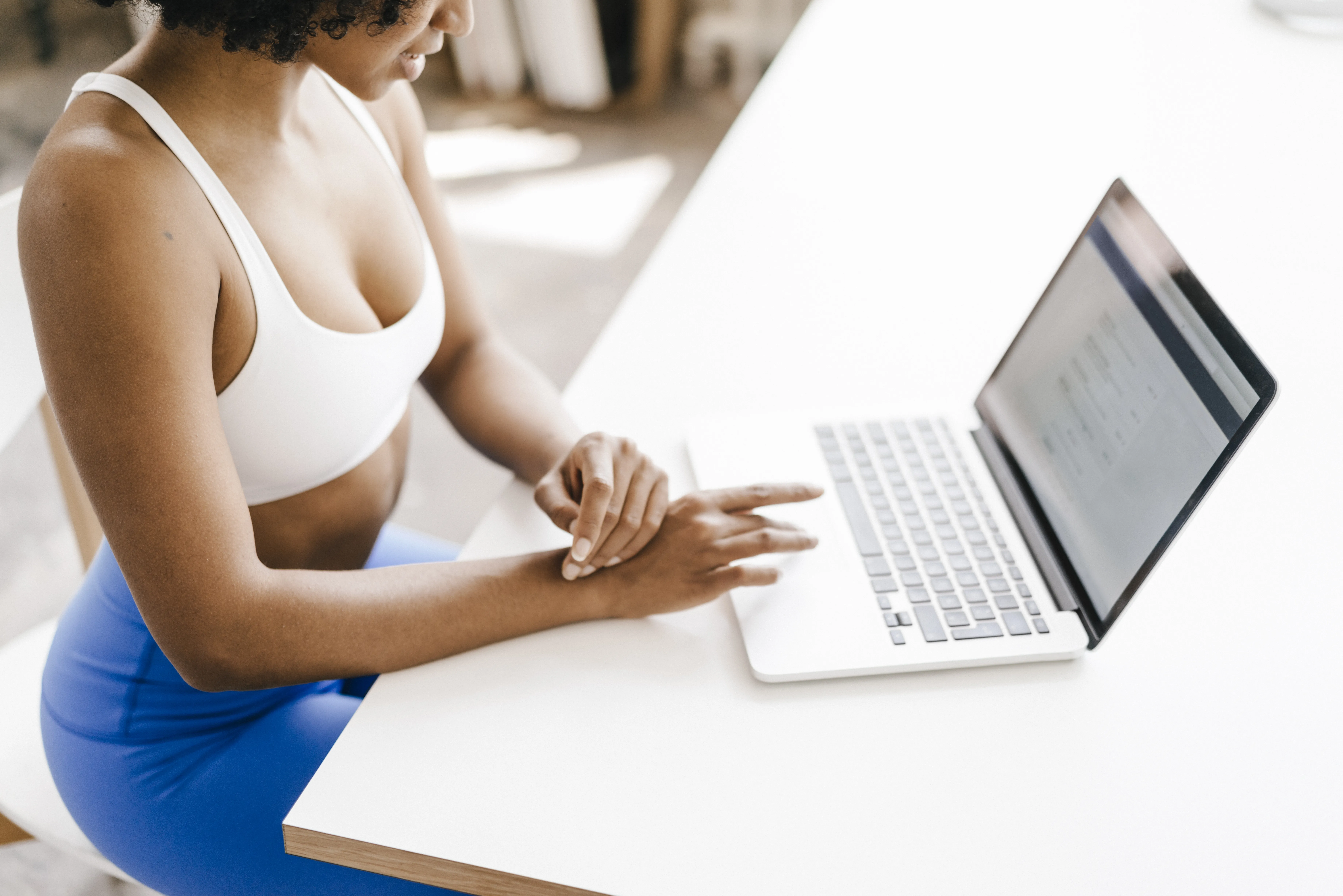 Frau in Sportkleidung nutzt den Computer, um ihre Online-Zahlung für das Training zu erledigen.