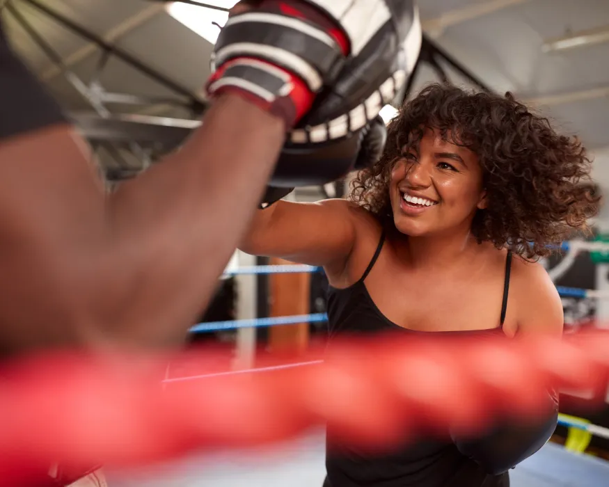 Frau boxt in einem Ring und lächelt, mit der Eversports Manager Software geht das trainieren gleich einfacher