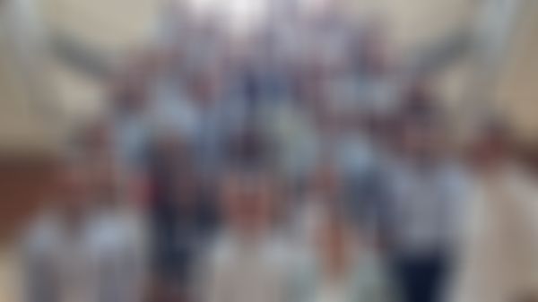 A large group of people standing on a staircase, posing for a photo. Many are wearing name tags and dressed in business casual attire.