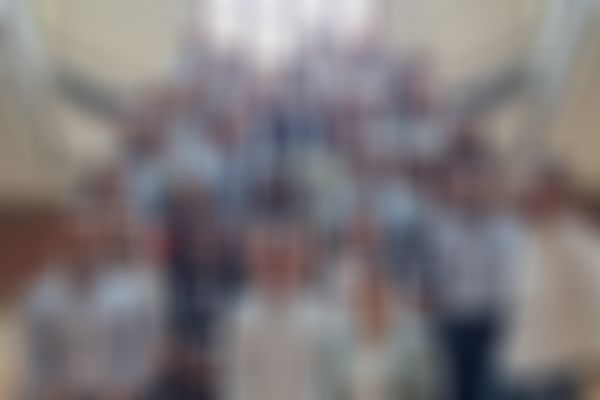 A large group of people standing on a staircase, posing for a photo. Many are wearing name tags and dressed in business casual attire.