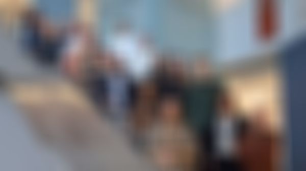 A group of people standing on a staircase inside a modern building, smiling and posing for a photo.