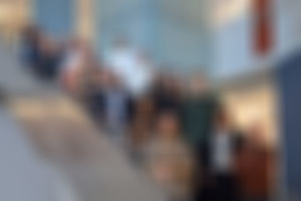 A group of people standing on a staircase inside a modern building, smiling and posing for a photo.