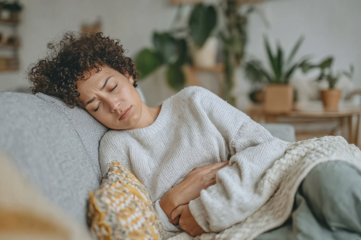 woman lying on sofa and holds her belly