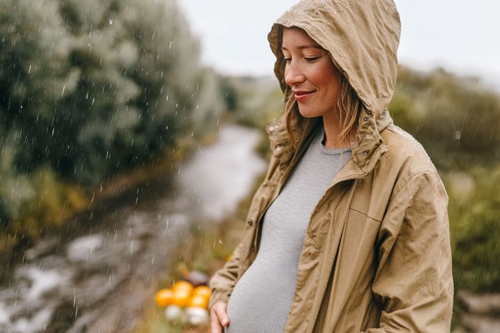 Schwangere Frau spaziert im Regen