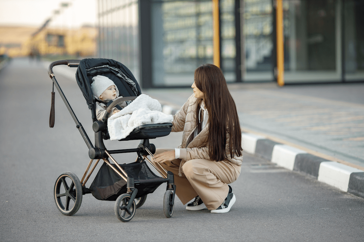 Mamička s bábätkom premýšľa, či kúpiť kočík alebo nosič – dilema budúcich rodičov. Mamička s bábätkom premýšľa, či kúpiť kočík alebo nosič – dilema budúcich rodičov.