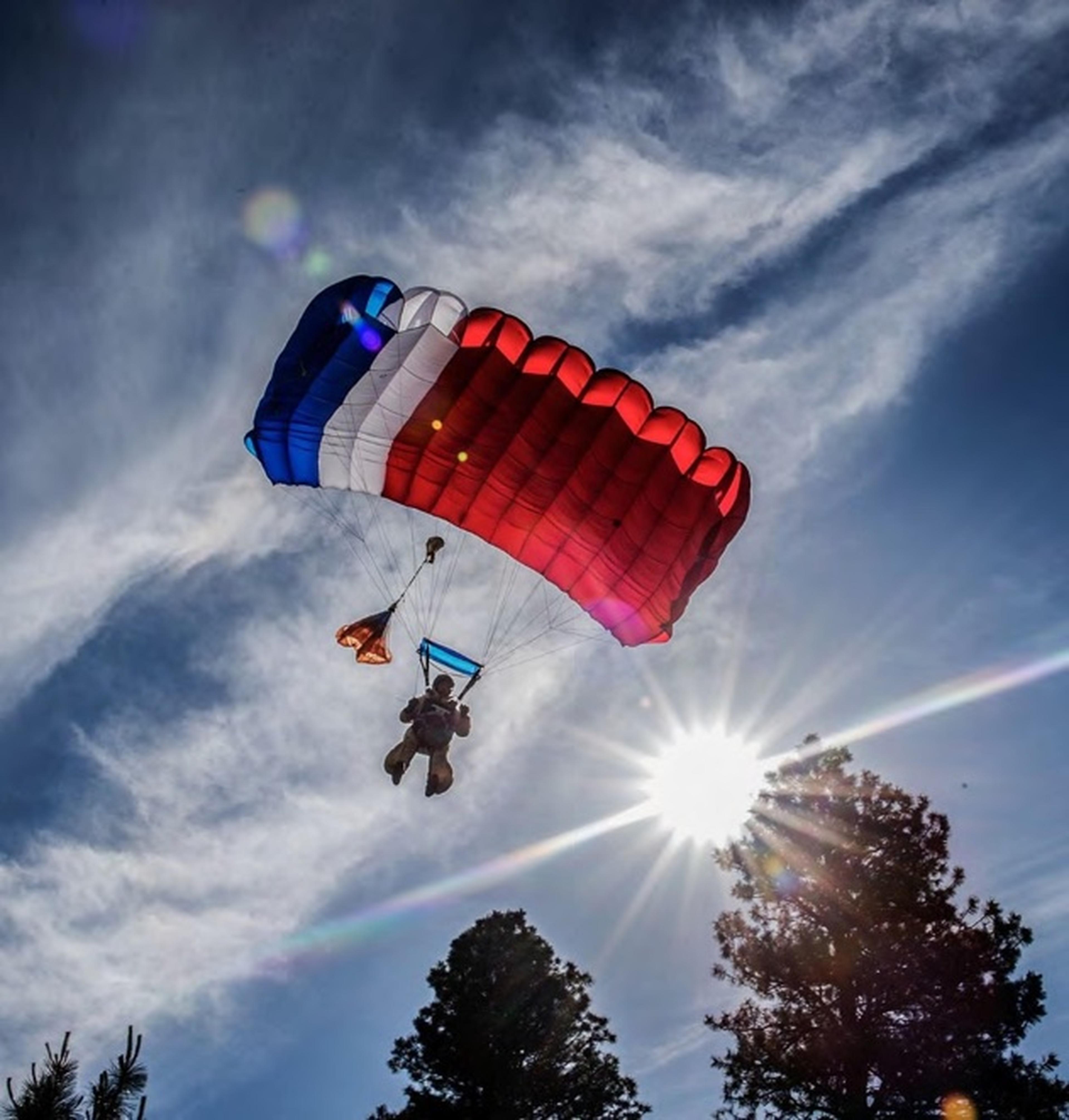 Parachutist descending under a red, white and blue canopy