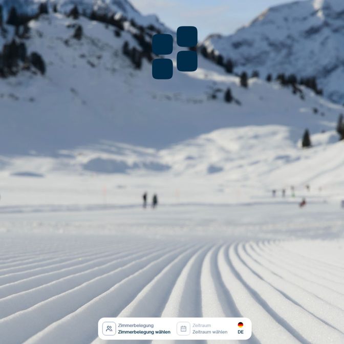 Snowy mountain landscape with groomed ski tracks in the foreground, people in the distance, and snow-covered trees and peaks under a clear sky.