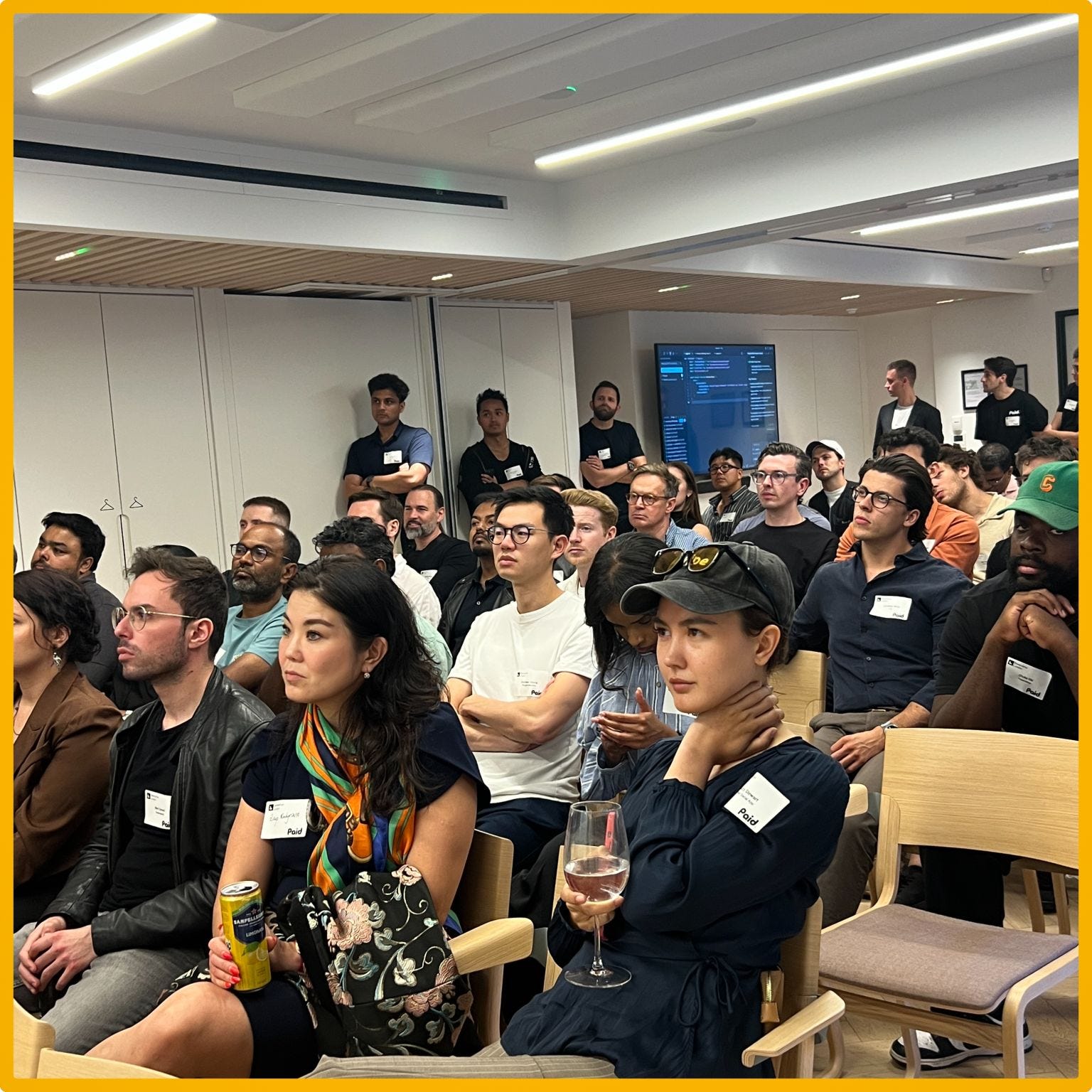 A diverse group of people seated in a modern conference room, attentively listening to a presentation.