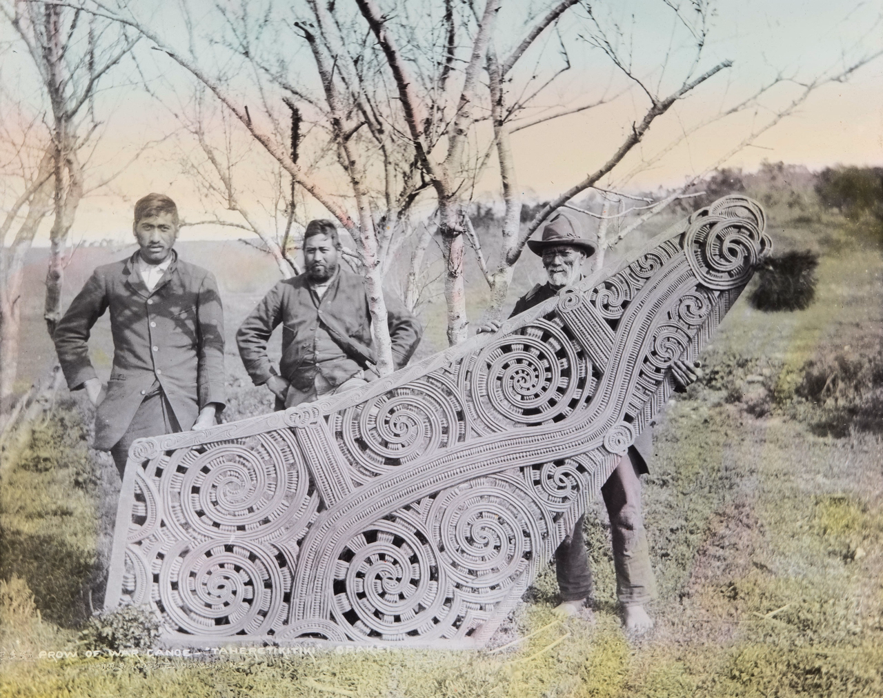 Three men with the large carved prow of the waka taua 'Taheretikitiki' in Ōrākei. Canterbury Museum 1975.203.24174