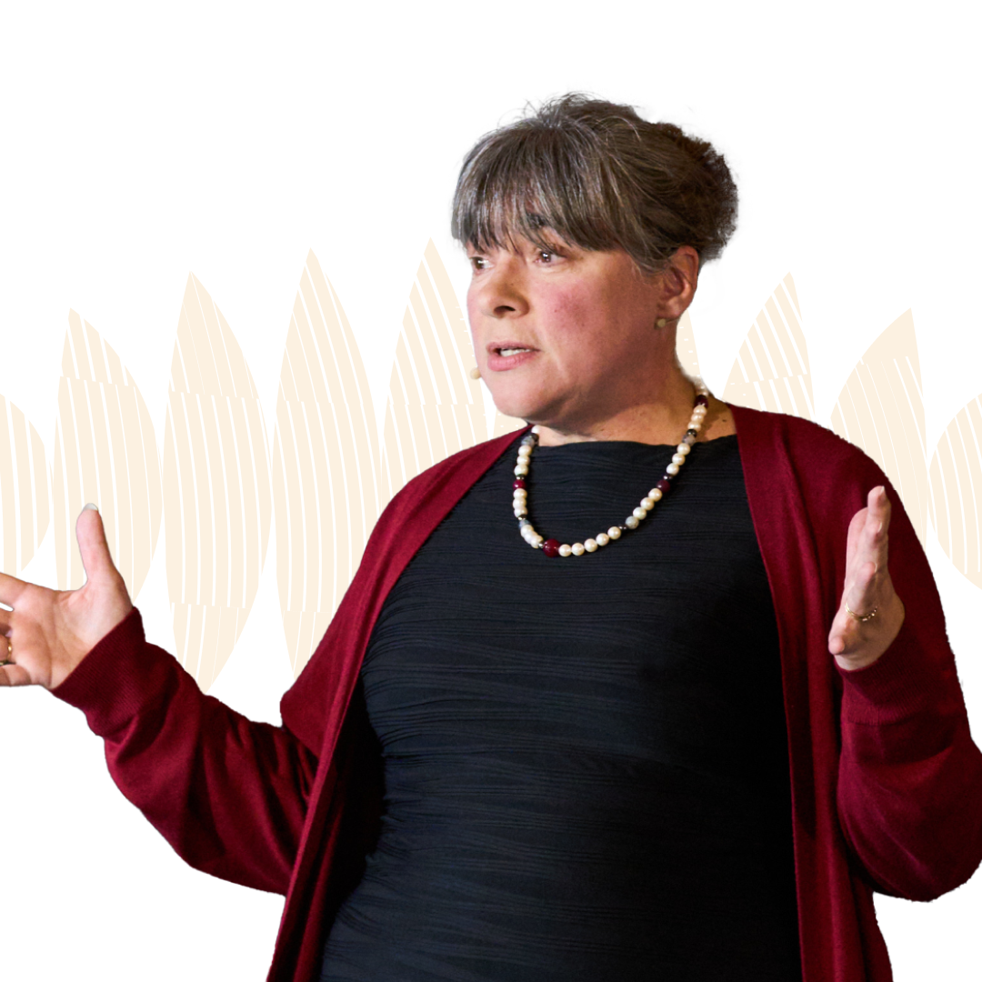 Eve Poole OBE gestures with both hands while speaking, against a white background with abstract patterns.
