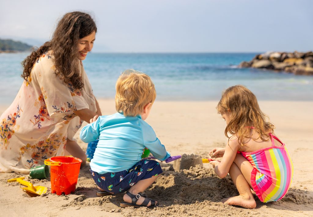 kids playing on the beach with their mom