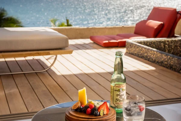Terrace table with fruit, a drink and a lounger, with the sea in the background
