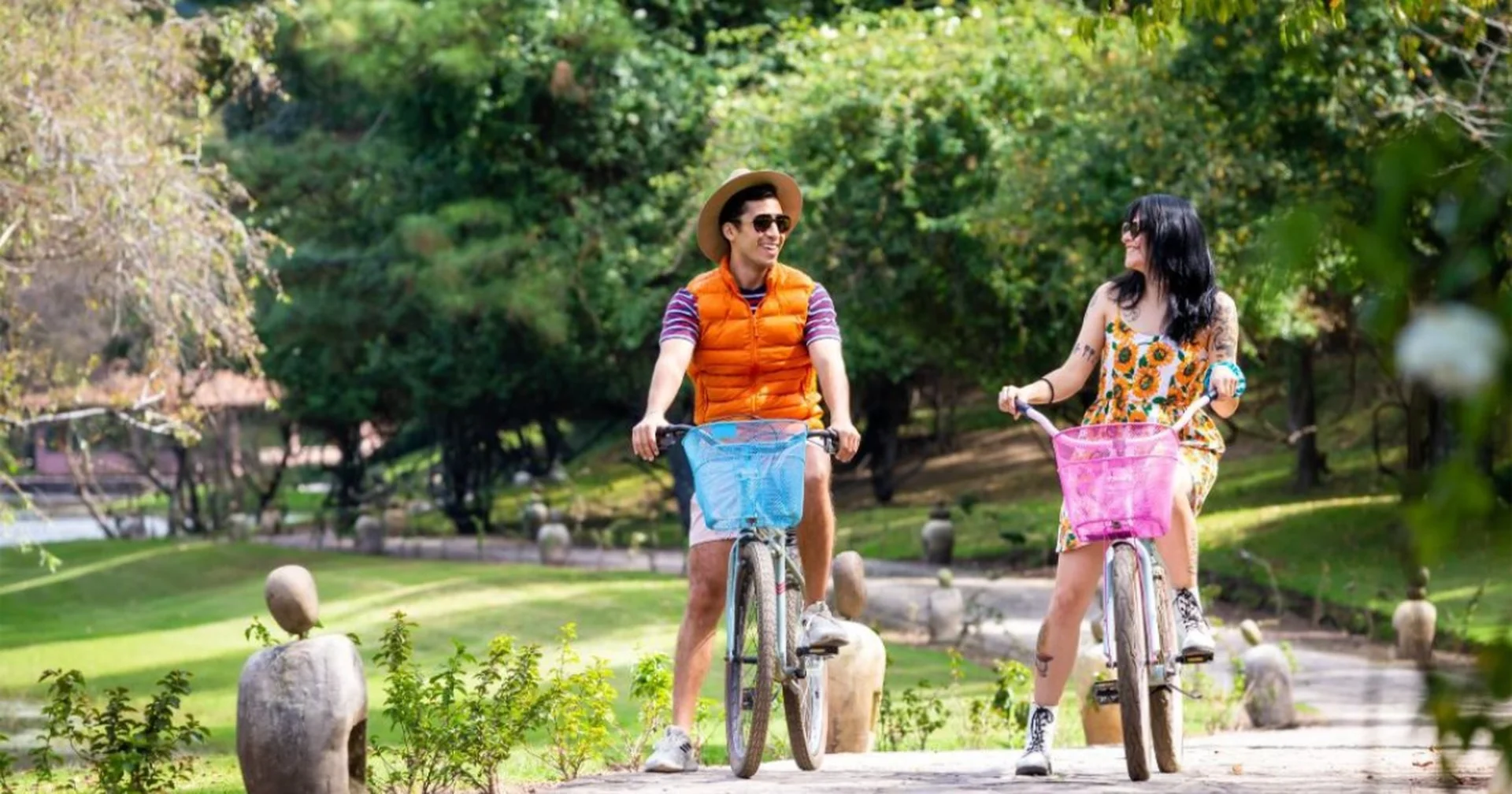 Couple riding bicycles along a tree-lined path on a sunny day
