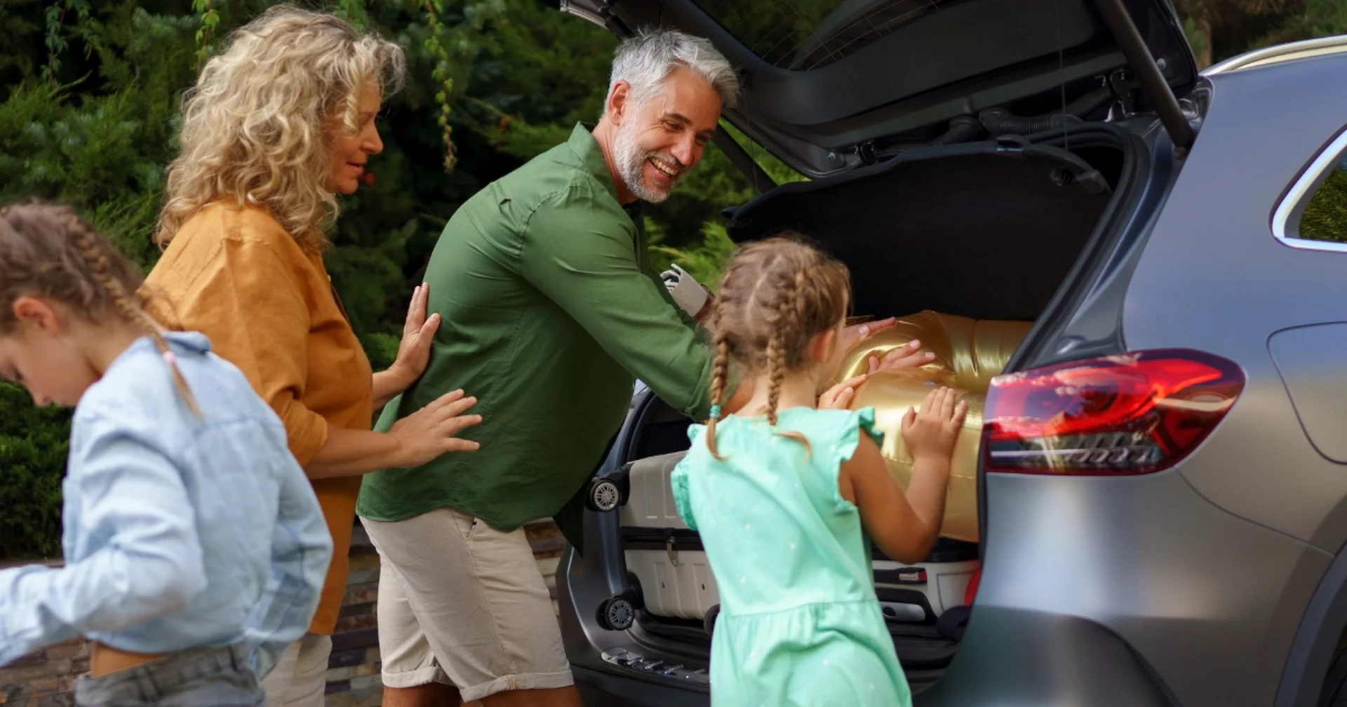 Family loading luggage into the back of an SUV before a road trip