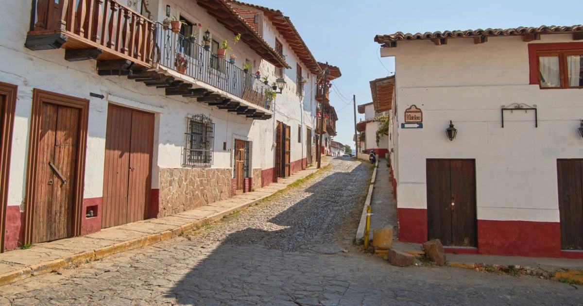 Cobblestone street in Tapalpa lined with whitewashed houses and wooden balconies