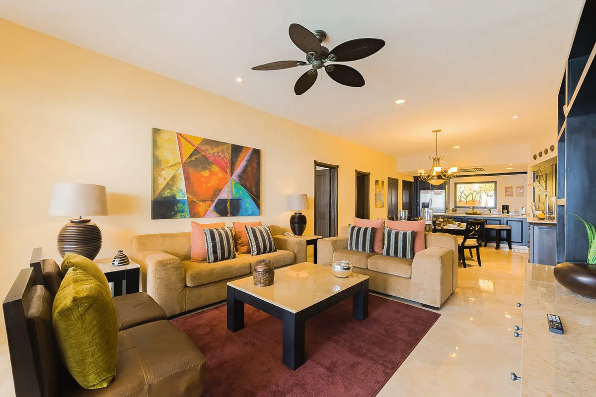 Sophisticated living area with modern decor, vibrant artwork, plush sofas, elegant lighting, and a ceiling fan in a luxury resort setting.