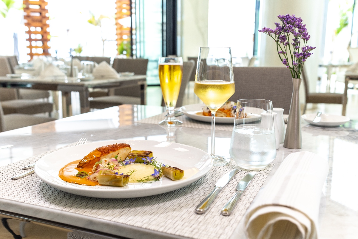 Gourmet plated entr&eacute;e with white wine and water at Garza Blanca Cabo's elegant resort restaurant