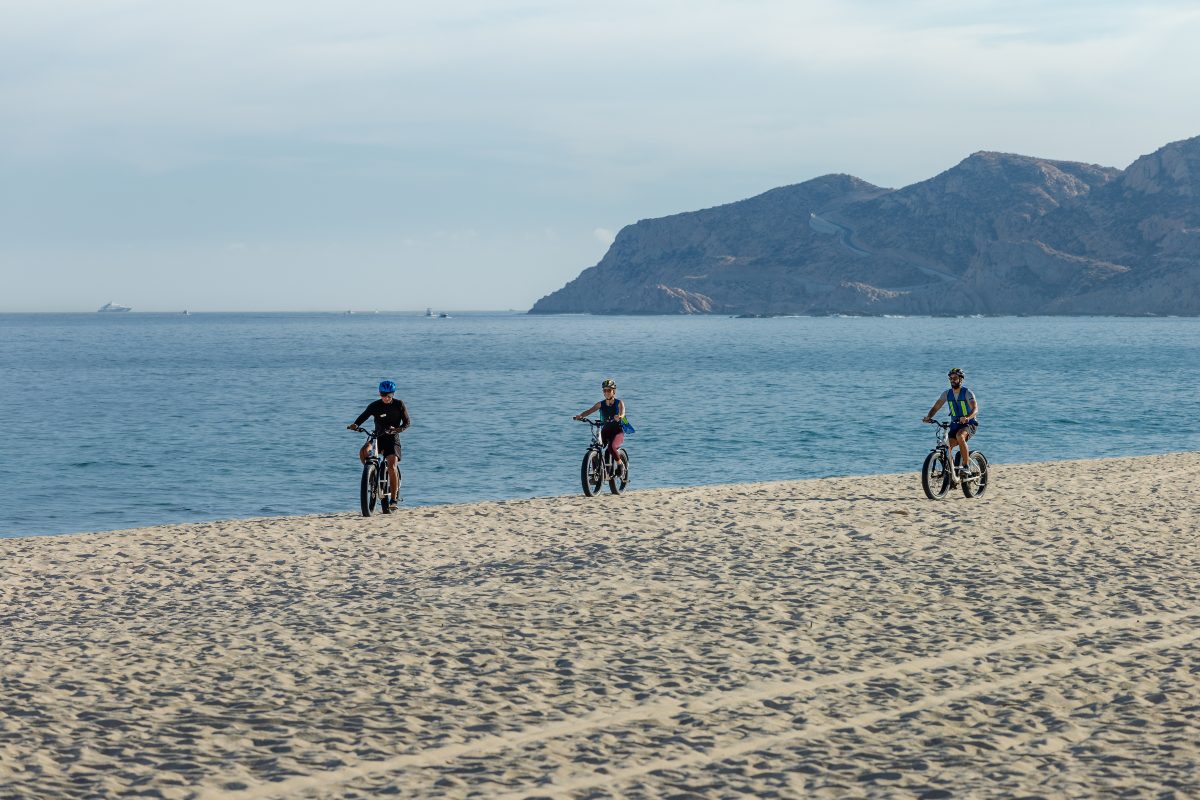 friends riding bikes at Garza Blanca Cabo beach