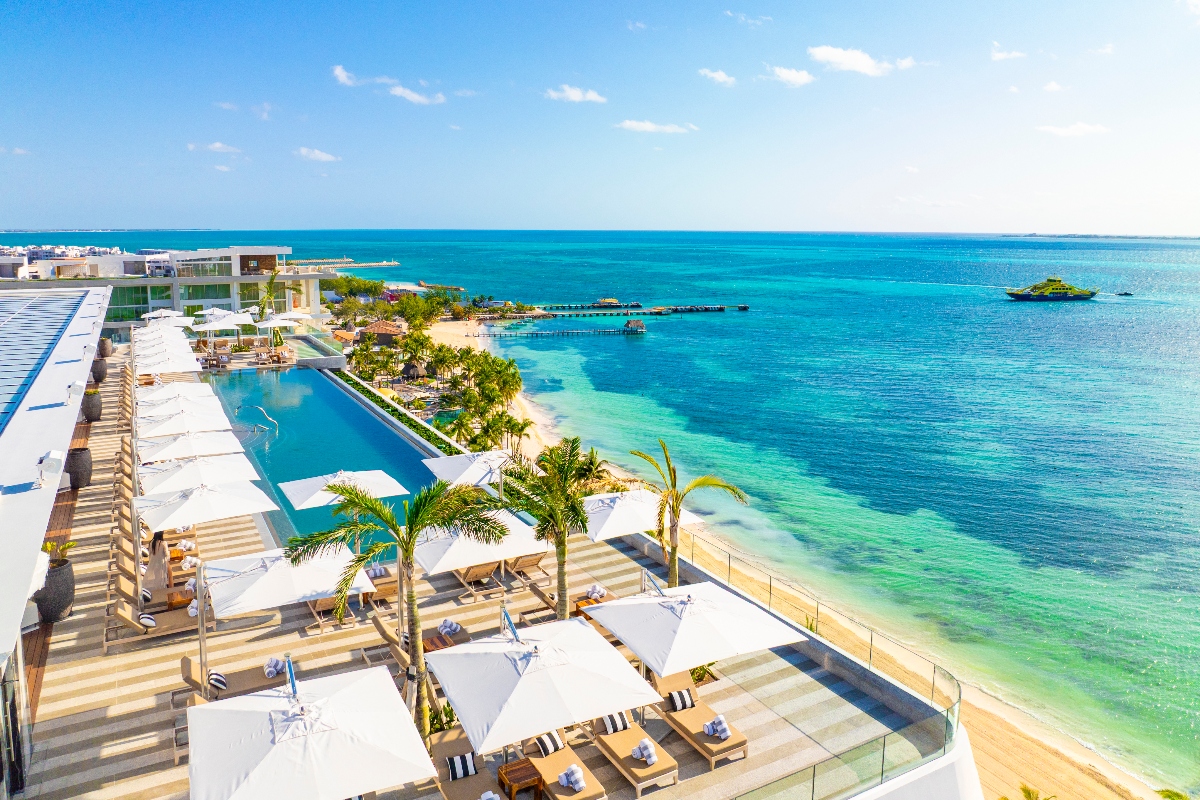 Aerial view of Hotel Mousai Cancun, featuring an infinity pool, white sun loungers, and turquoise Caribbean waters.