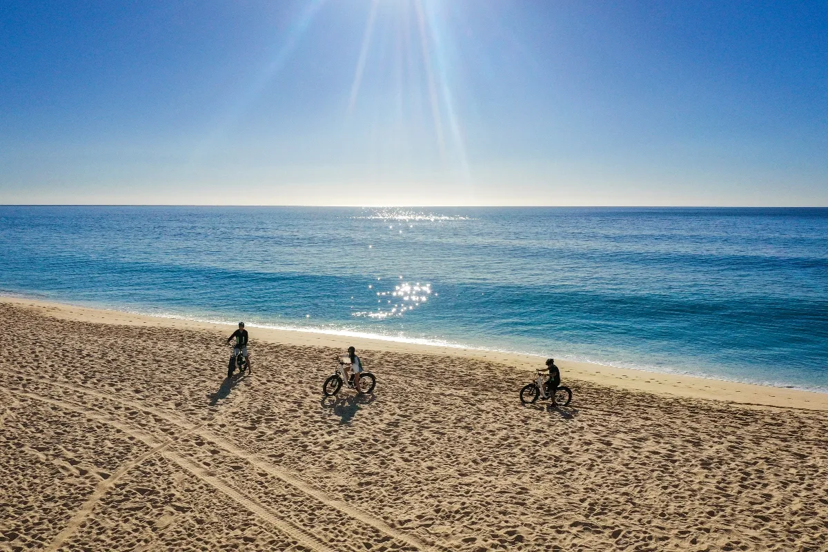 Three cyclists ride fat-tire bikes along Garza Blanca Cabo beach