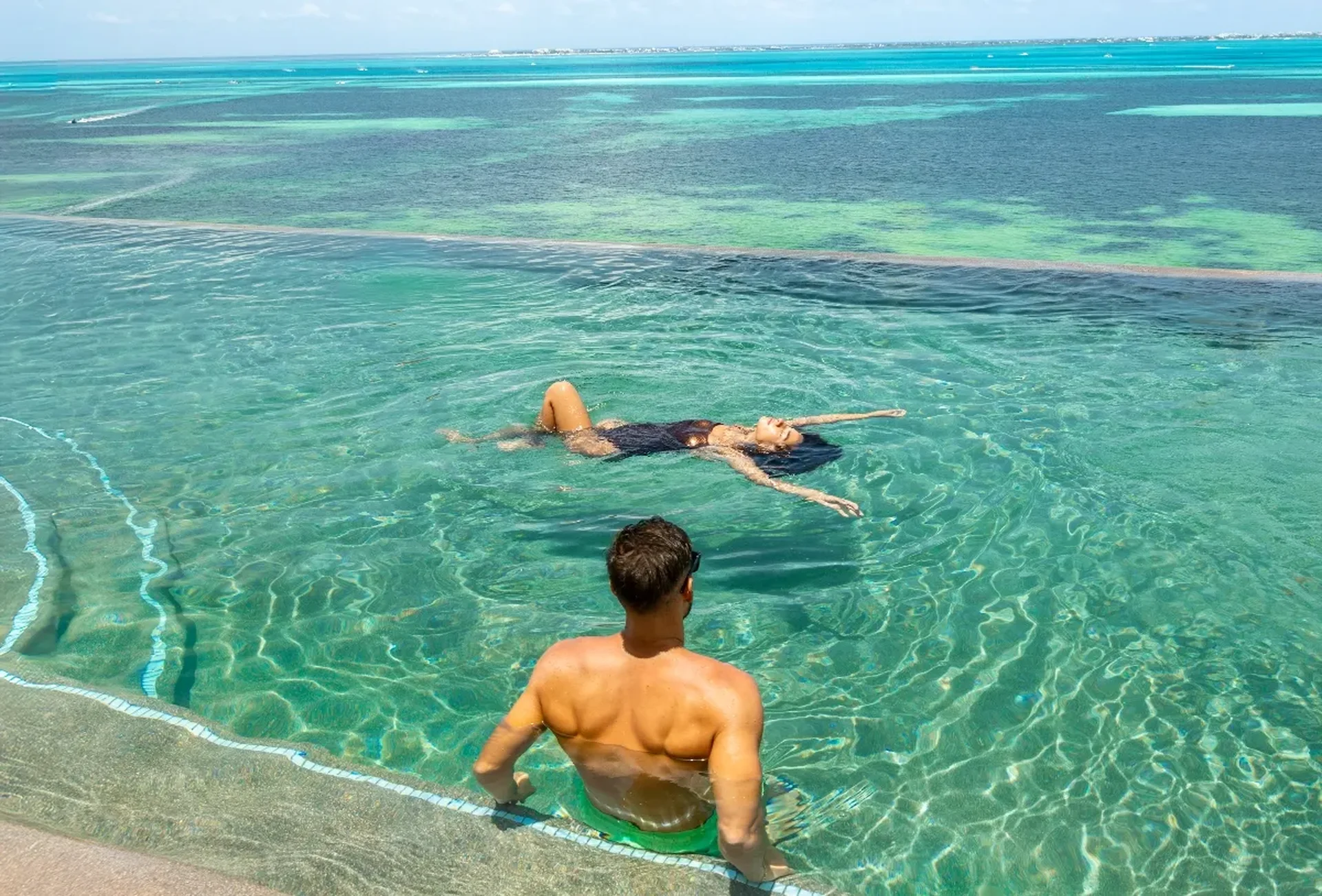 Pareja relajándose en la alberca del rooftop frente al mar de Hotel Mousai Cancún