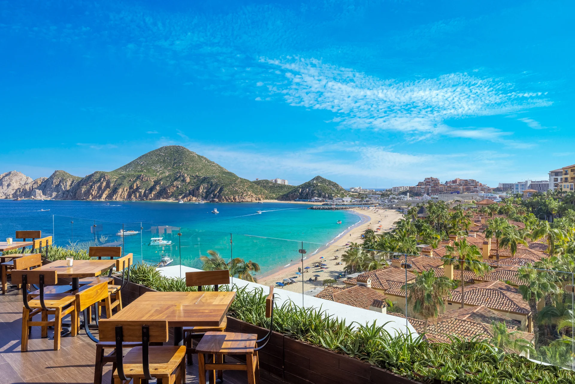 Escape to the Extraordinary: ocean-view terrace at Garza Blanca, Mexico, overlooking turquoise bay, palm-lined beach and hills.