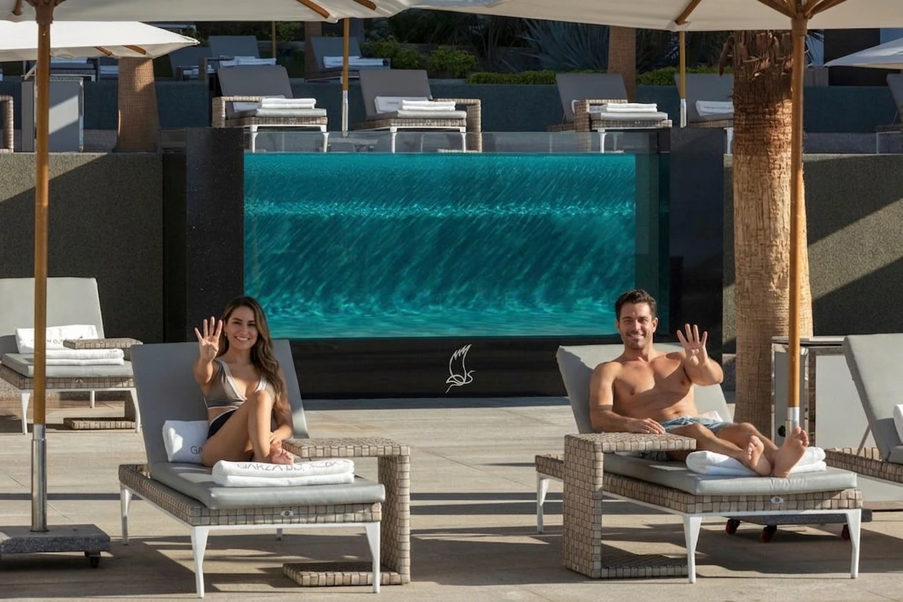 couple saying hi to the camera while rest in the pool chairs