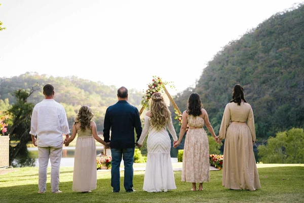 Mesa de novios con arco floral y letrero de neón ante el ventanal con vista al lago