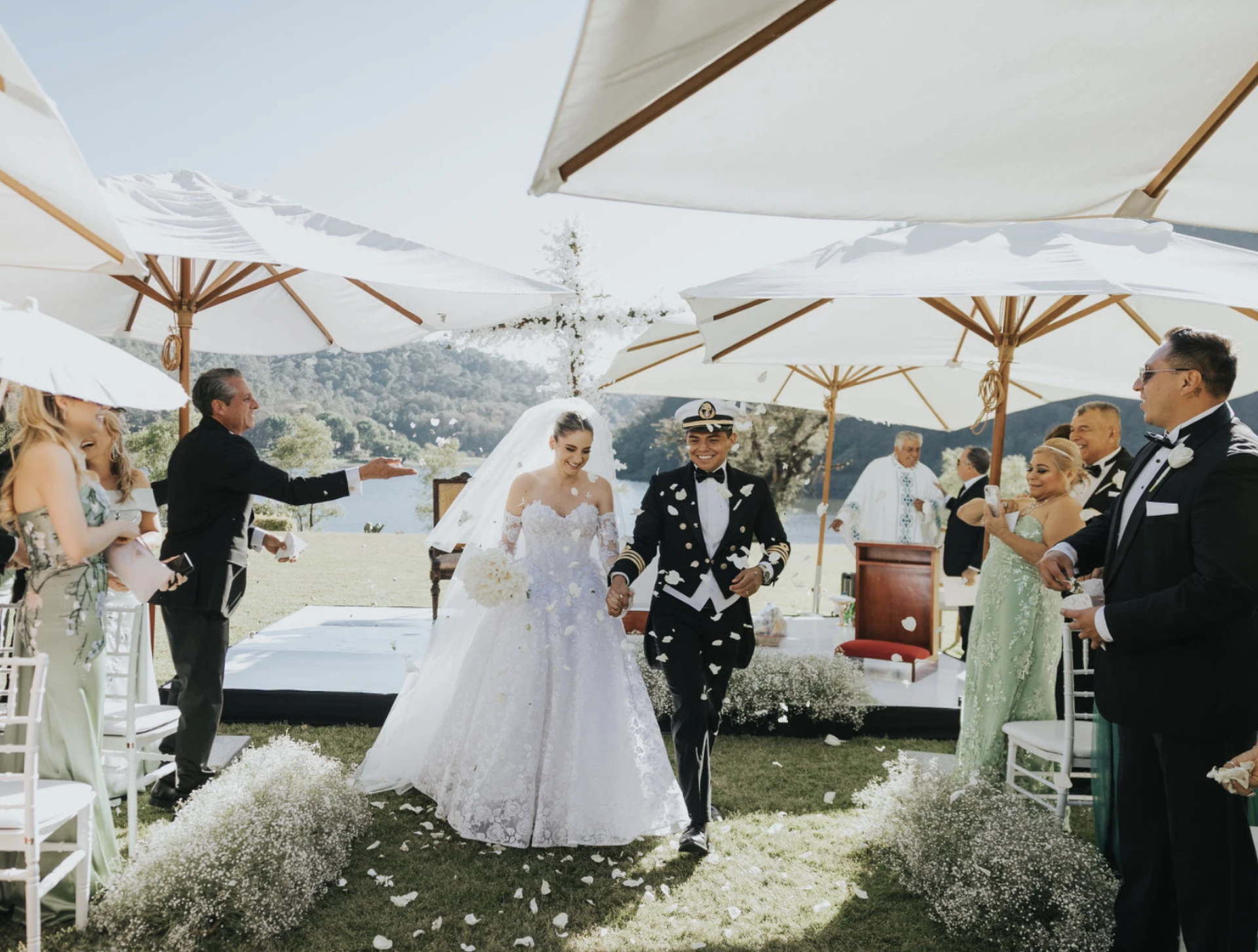 Novios besándose en la terraza de piedra, el novio de uniforme naval, junto al lago