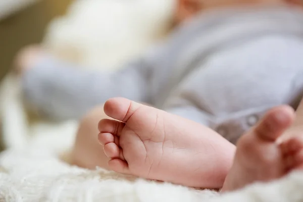 Close-up of a baby's feet as they lie down on a soft surface.