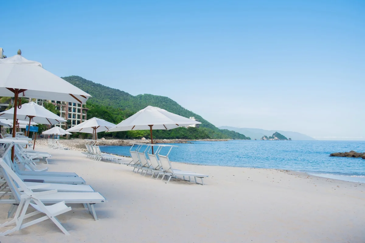 Rows of white loungers and umbrellas facing a calm turquoise sea at Garza Blanca Puerto Vallarta
