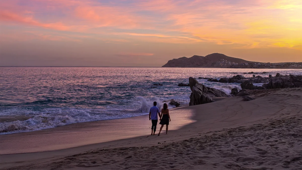 Couple walking on the beach at sunset at Garza Blanca Los Cabos
