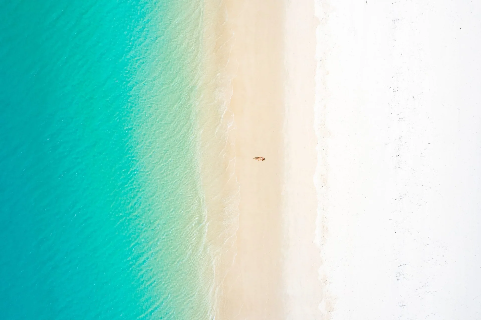 Mujer recostada en una playa de arena blanca con aguas turquesa en Cancún