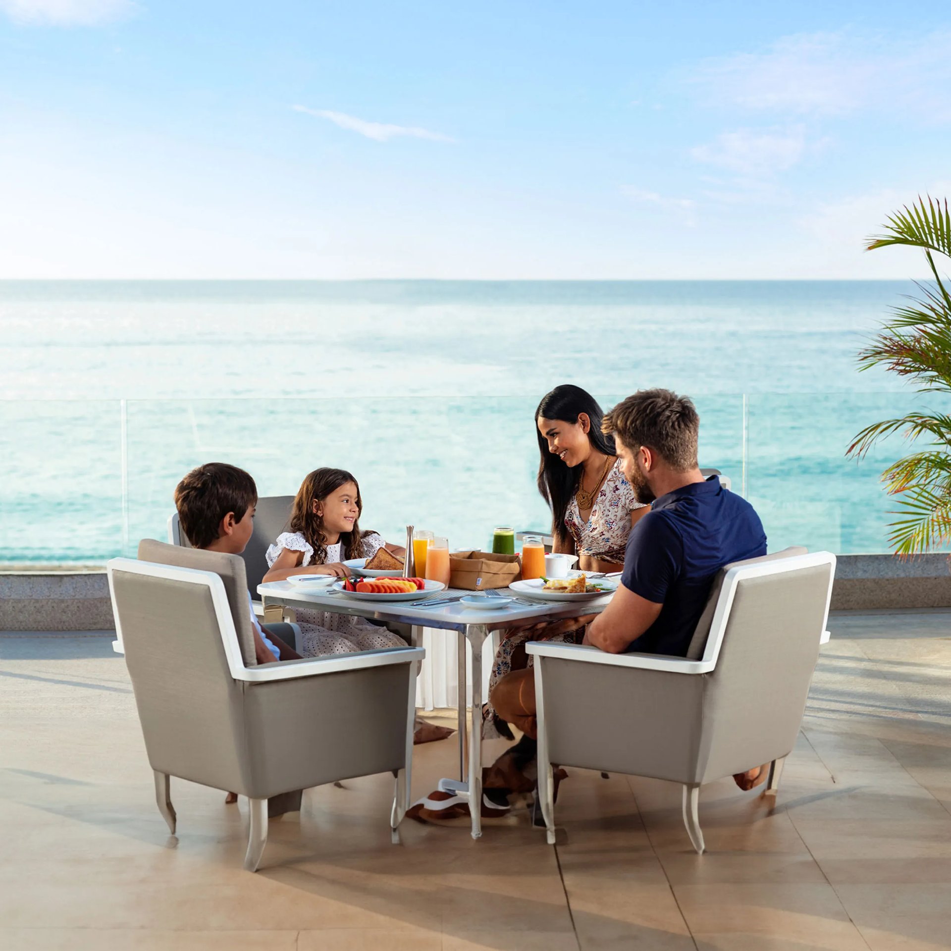 Family dining al fresco at Garza Blanca, a luxury all-inclusive beach resort in Mexico, overlooking the turquoise ocean.