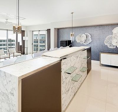 Modern kitchen with marble island, pendant lights, and decorative wall art. Large windows provide ample natural light.