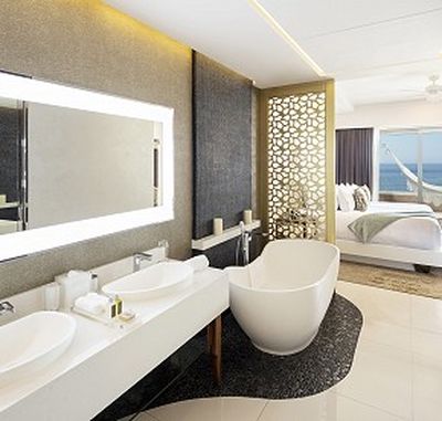 Luxurious bathroom with a freestanding tub, double sinks, large mirror, and decorative screen, leading to a bedroom with an ocean view.