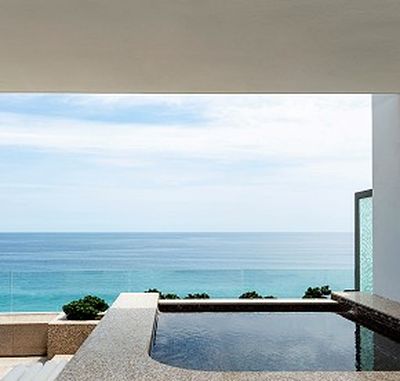 Infinity pool overlooking a serene ocean view, framed by a modern architectural structure under a clear blue sky.