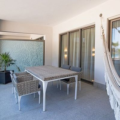 Modern patio with a wicker dining set, frosted glass divider, potted plant, and a hammock hanging on the right.
