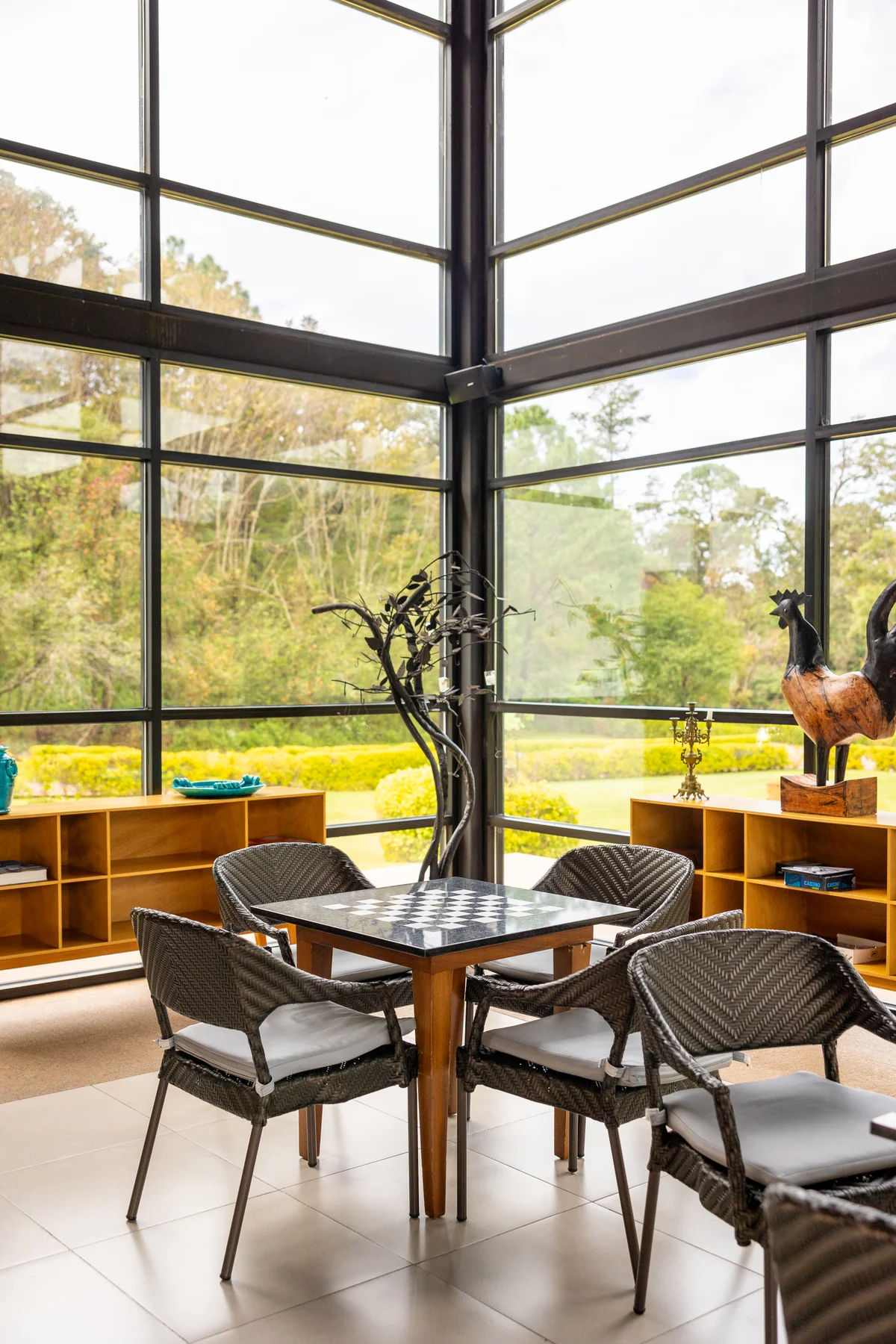 Mesa de juego con sillas en un rincón acristalado del lounge con vista al bosque