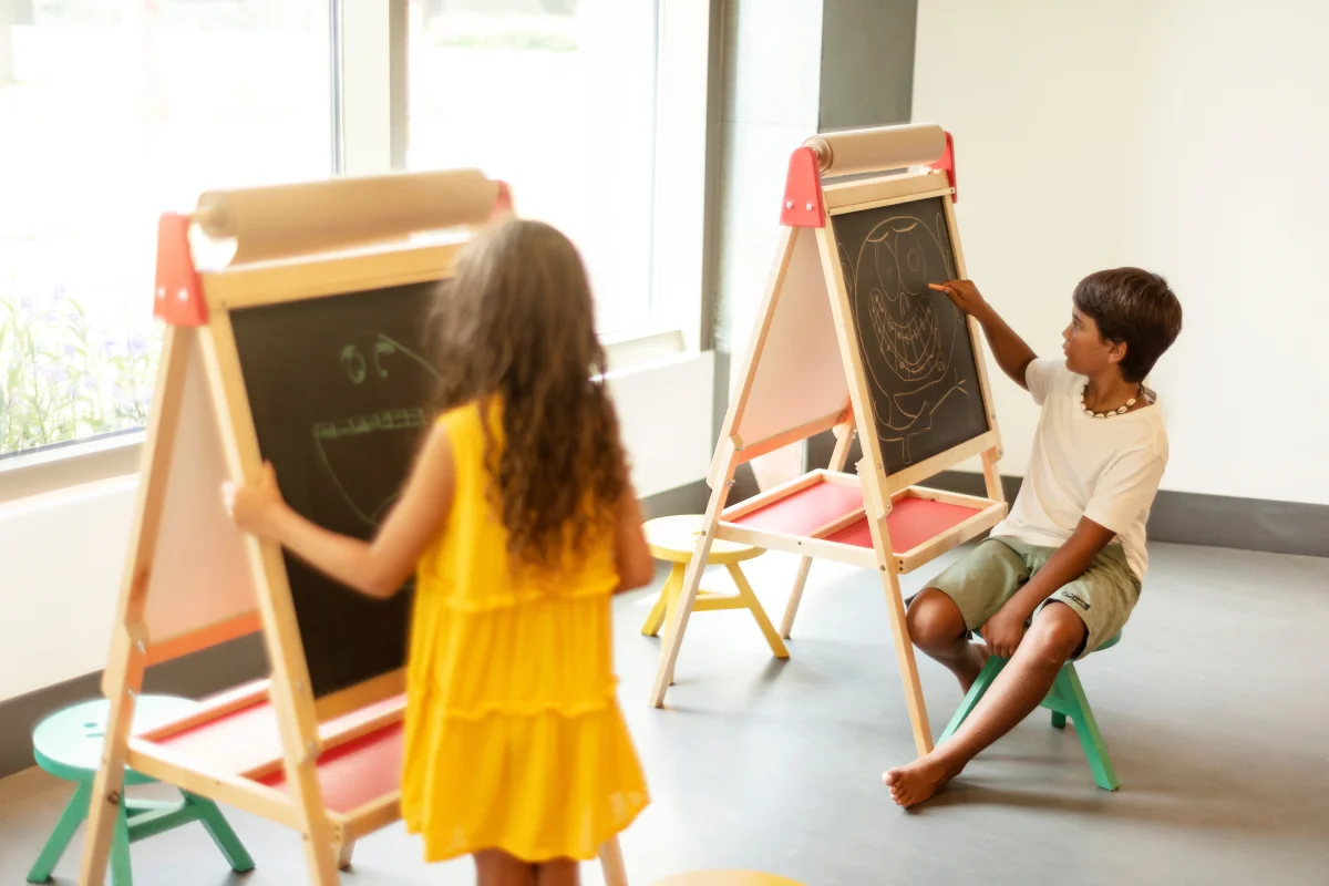Two kids drawing on chalkboard easels at the Kids’ Club of Garza Blanca Los Cabos