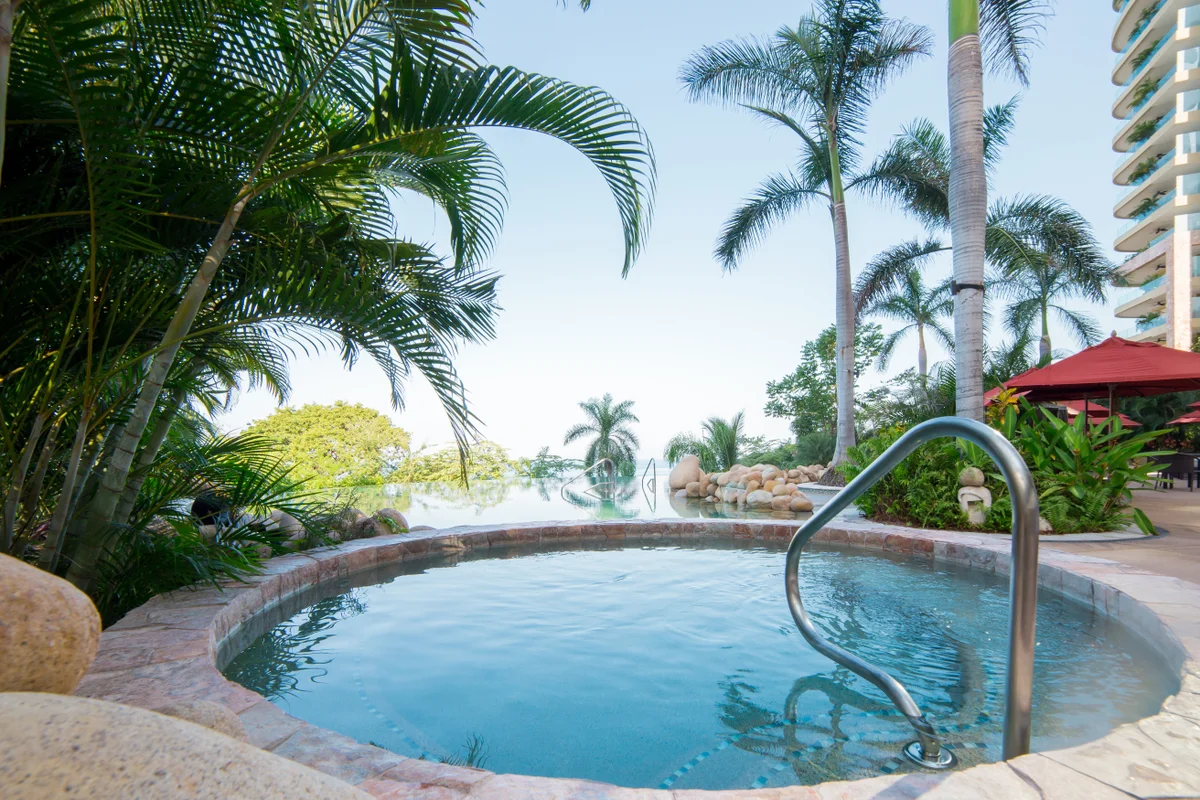 Outdoor Jacuzzi surrounded by palm trees at Garza Blanca Puerto Vallarta