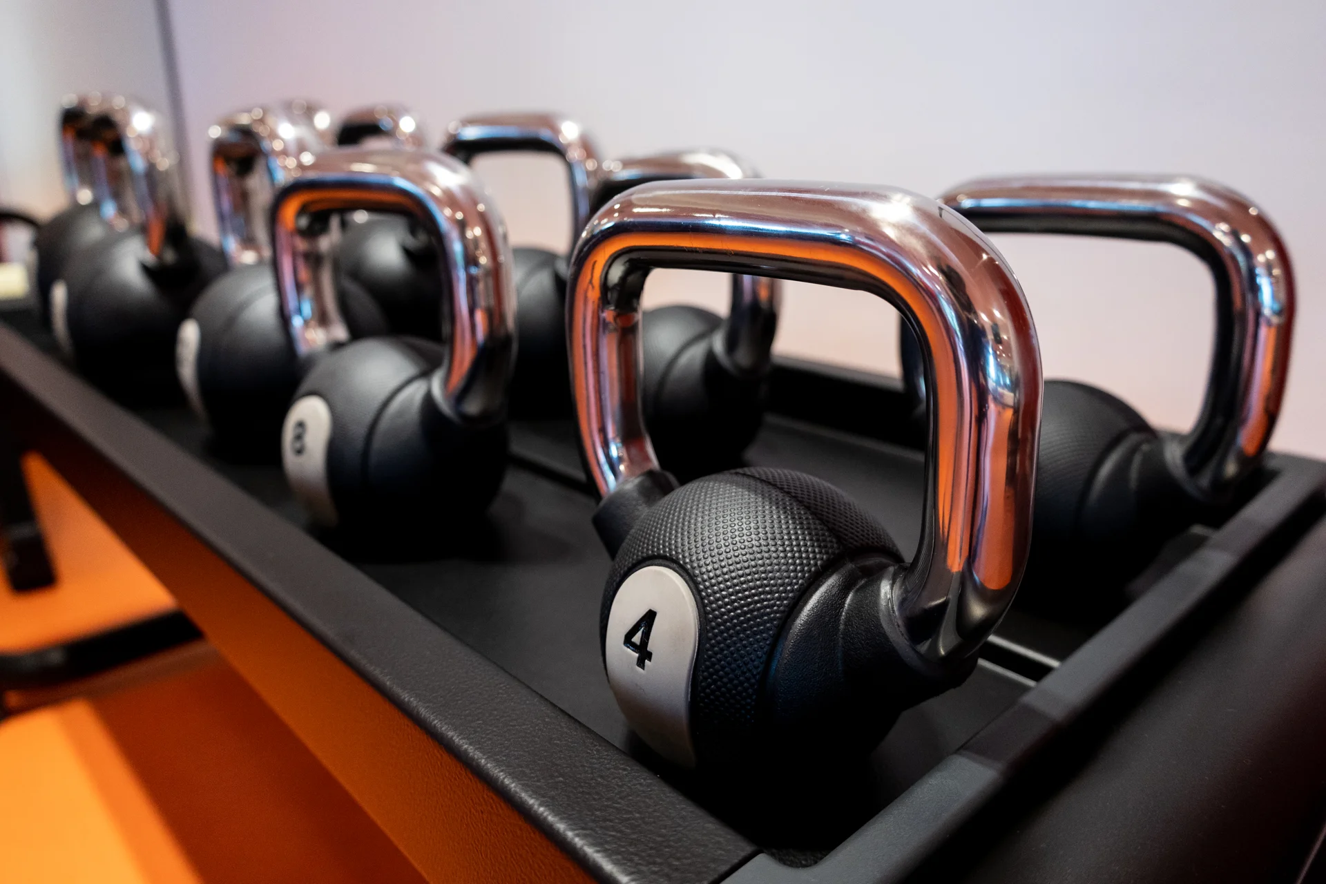 Man exercising on a WaterRower machine in a gym, wearing a black shirt and patterned pants. Fitness equipment is visible in the background.