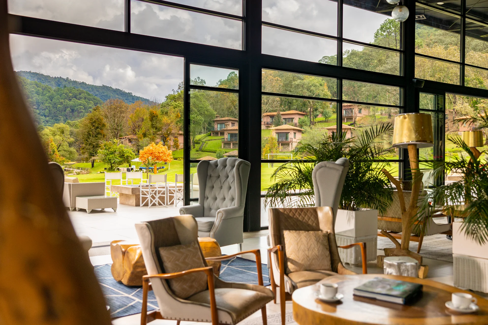 Armchairs and coffee table with mountain and cabin views through large windows